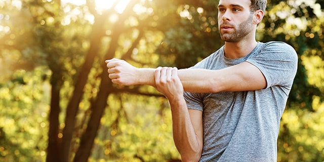 Man stretching arm outdoors