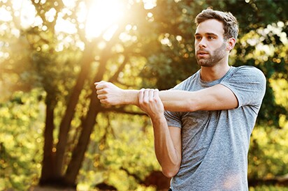 Man stretching arm outdoors